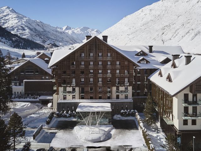 The Chedi Andermatt Hotel covered In snow with Swiss Alps in the background.