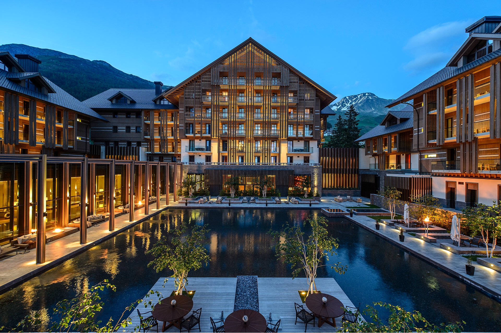 A view of The Chedi Andermatt exterior building with pool and night lights in summer.