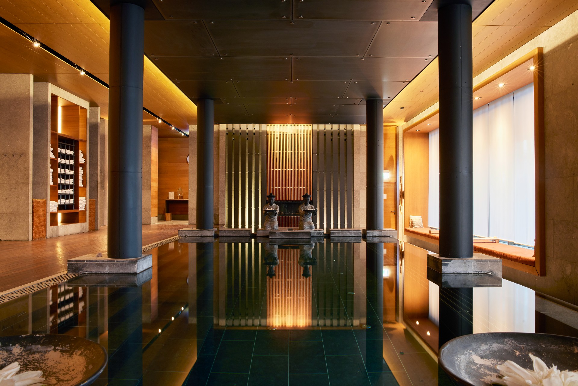 Indoor pool with 2 buddhas at the edge of it and large mighty columns. Relaxed atmosphere.