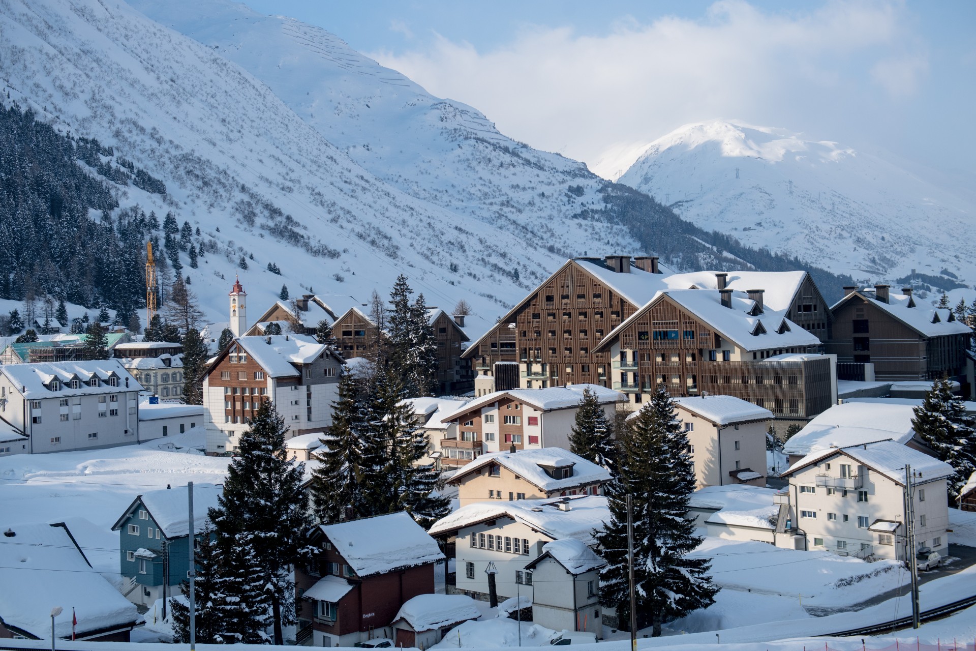 A Group Of Buildings In A Snowy Area With Mountains In The Background