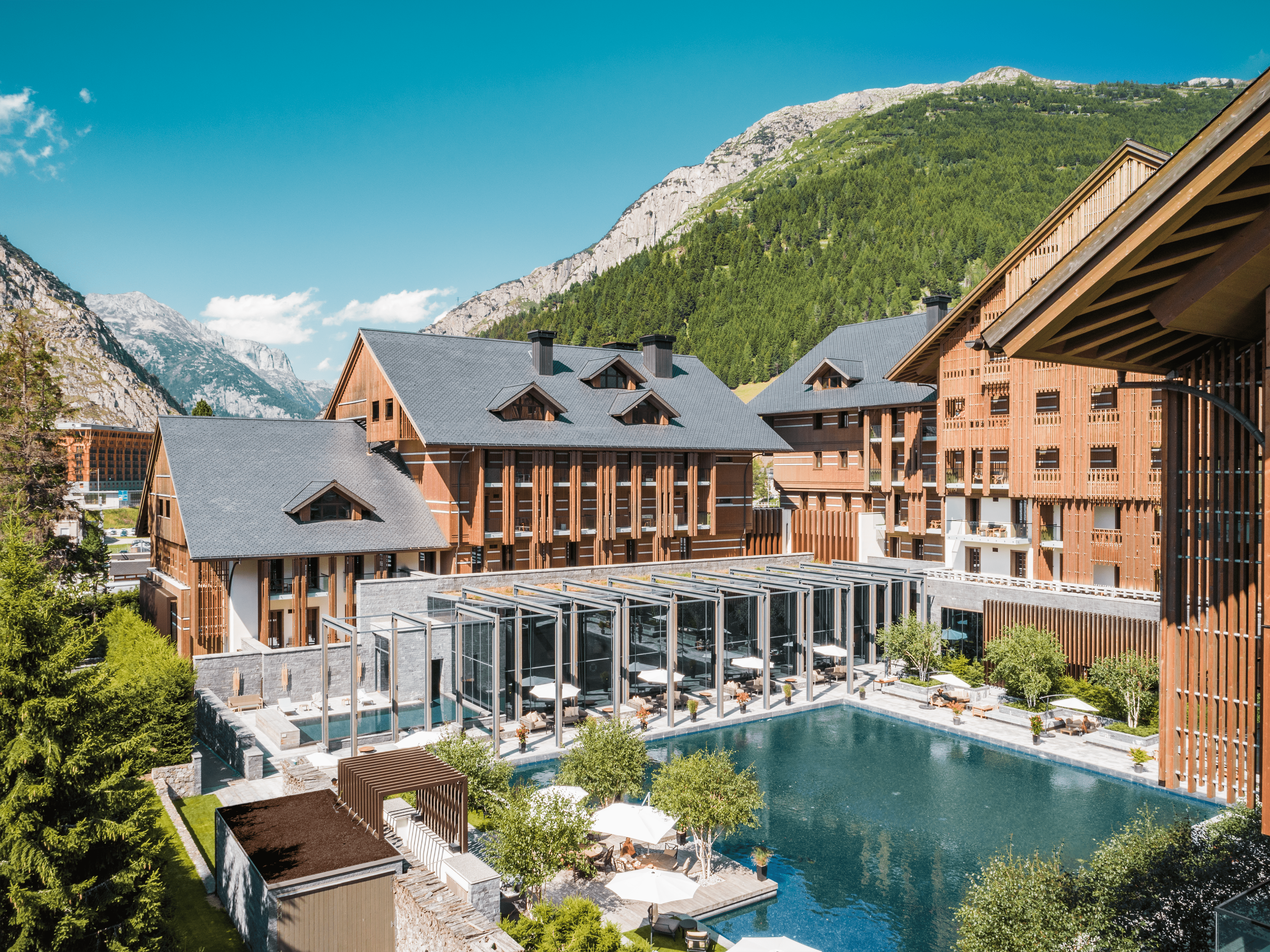 A Building With A Pool In Front Of It And A Mountain In The Background